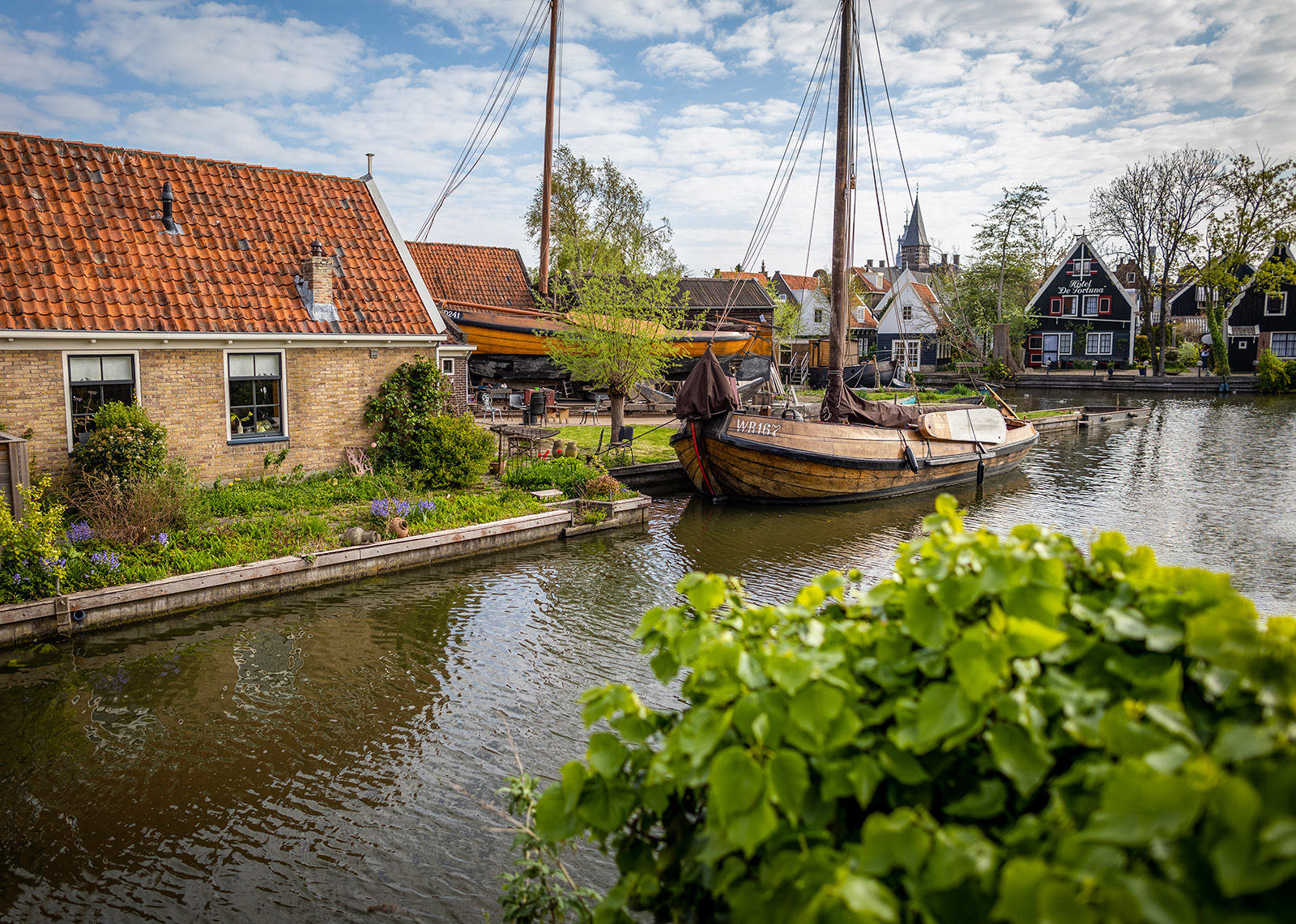 Shot of small river, houses, wooden boat.