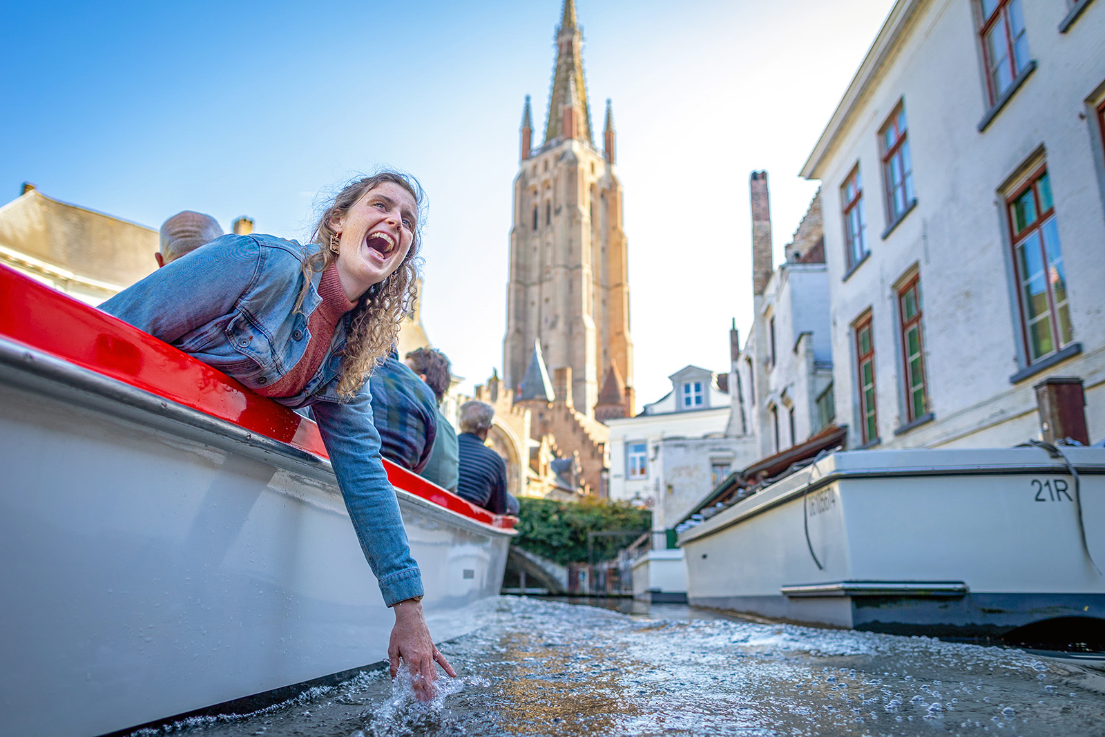 Woman leaning off a small boat trailing her hand in the water.