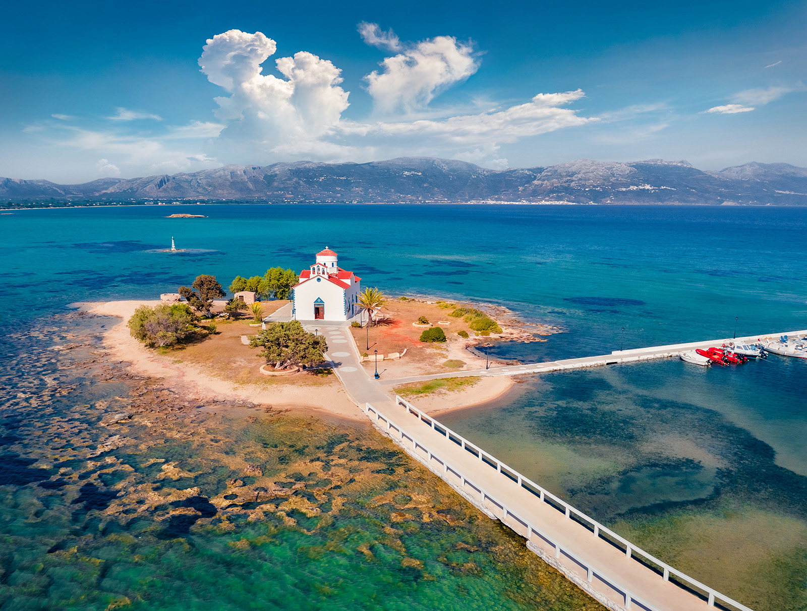 Shot of small island with church, two roads leading onto it, amidst ocean vista.