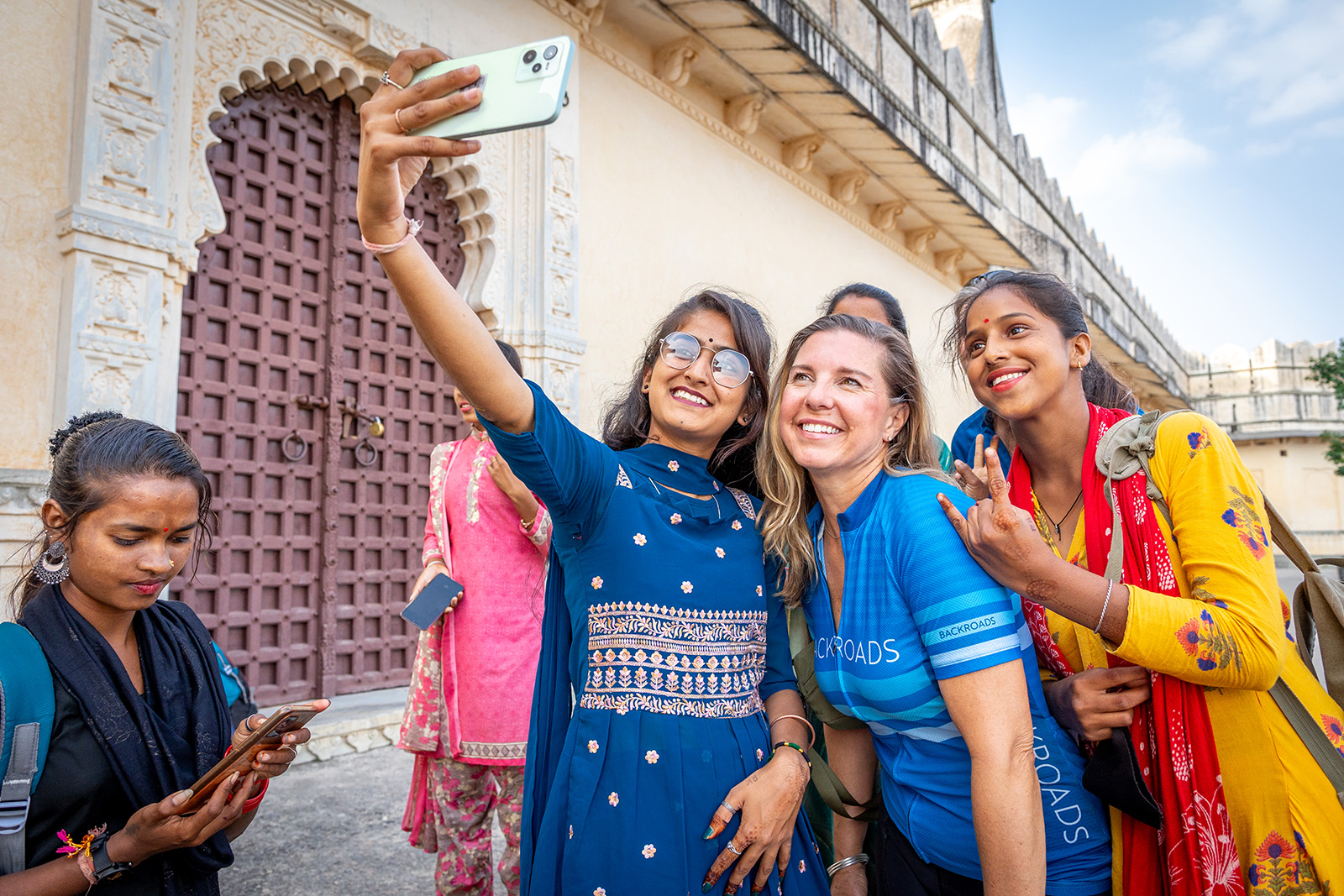 Group of people smiling while a girl is holding up a phone to take a photo