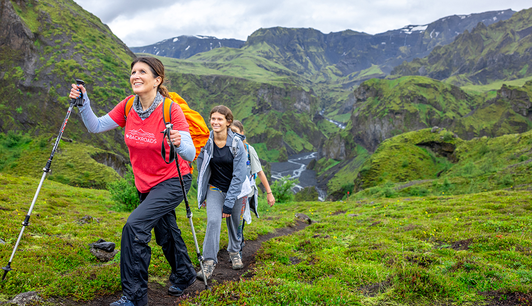 Group of women hiking up a dirt trail, with grassy mountains in the distance