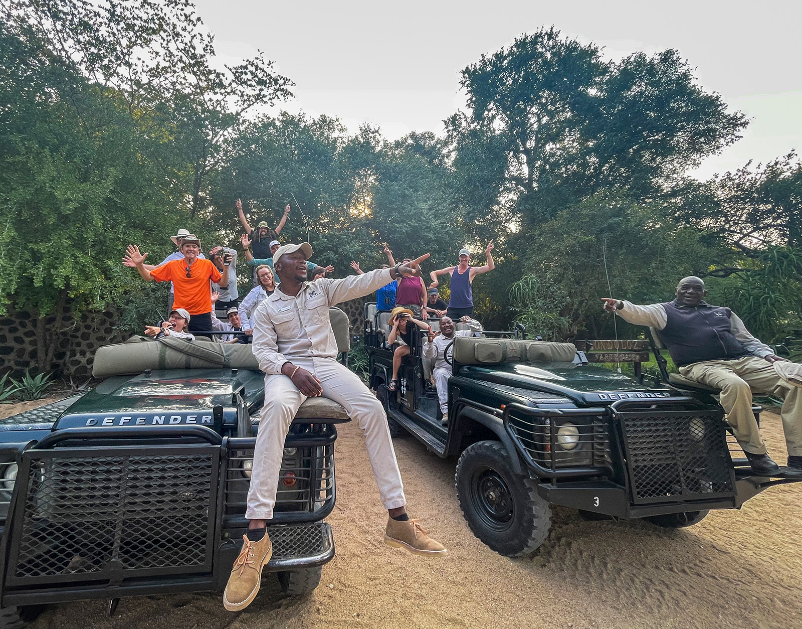 Tour guides sitting on hood of the cars pointing