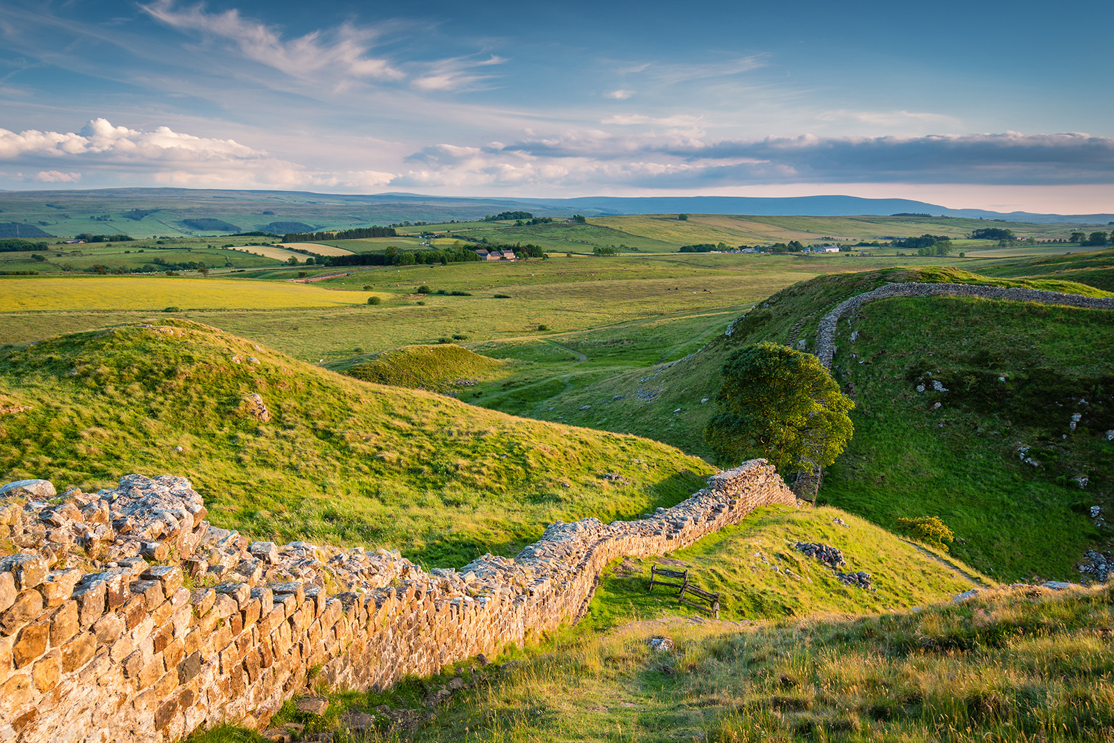 sloping green hills with stone wall