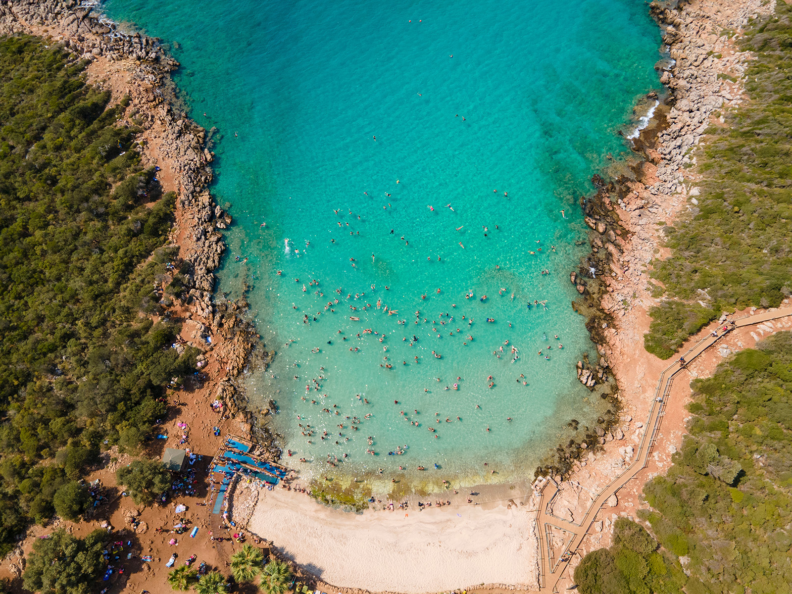 Sky view of a beach with people in the ocean and sand