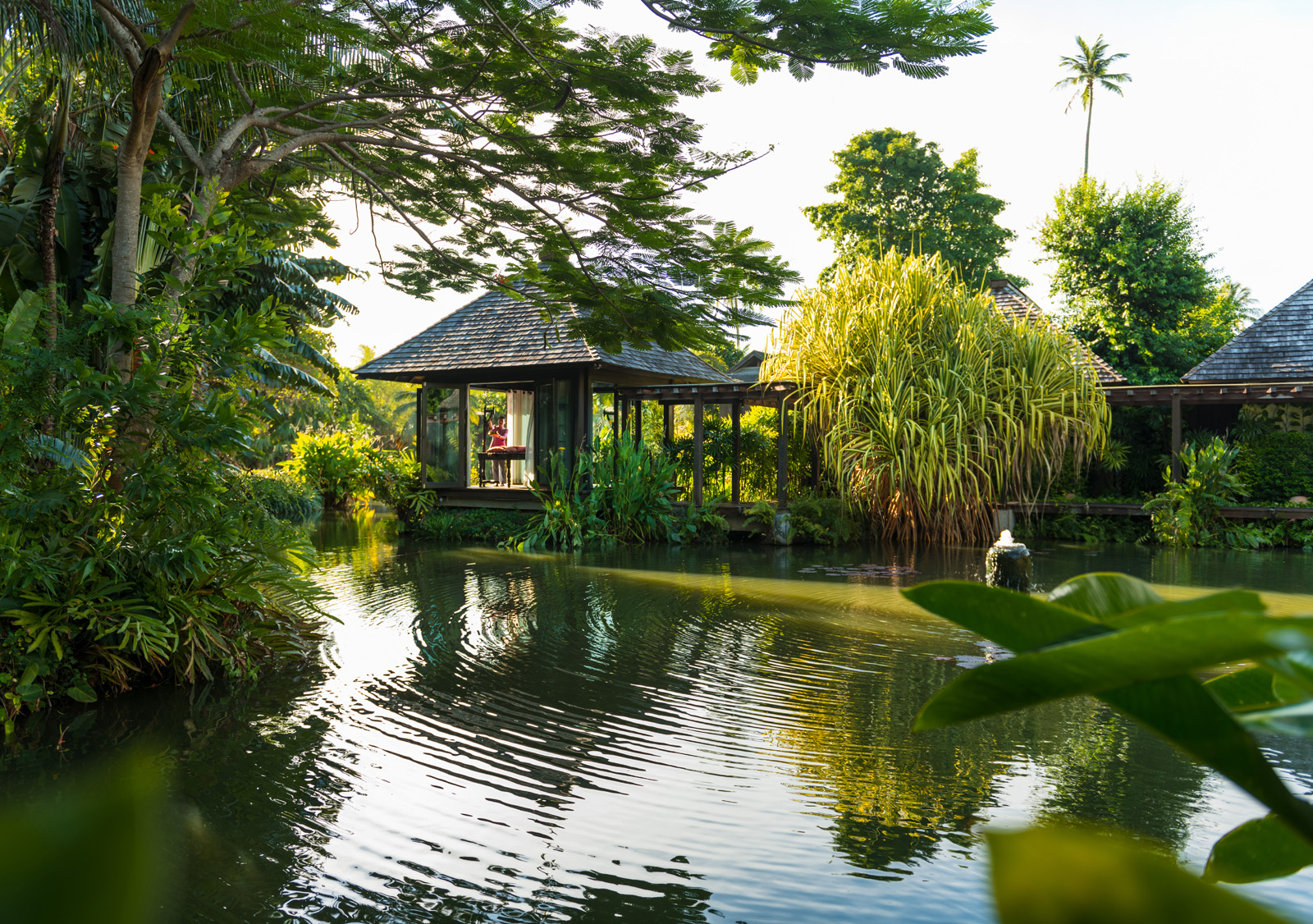 Lake with an outdoor hut above, surrounded by trees