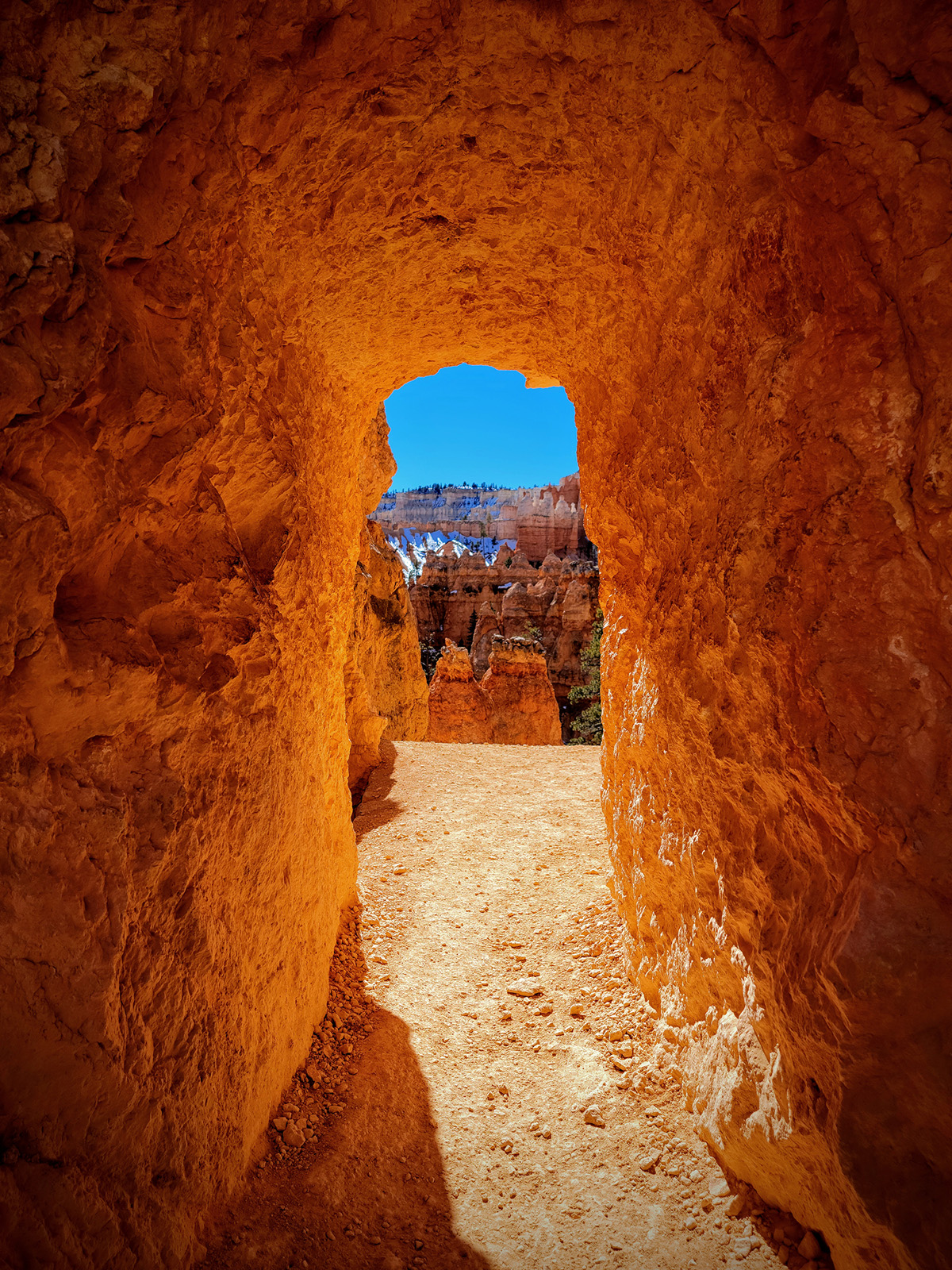 Orange tunnel of natural rock leading to a larger canyon