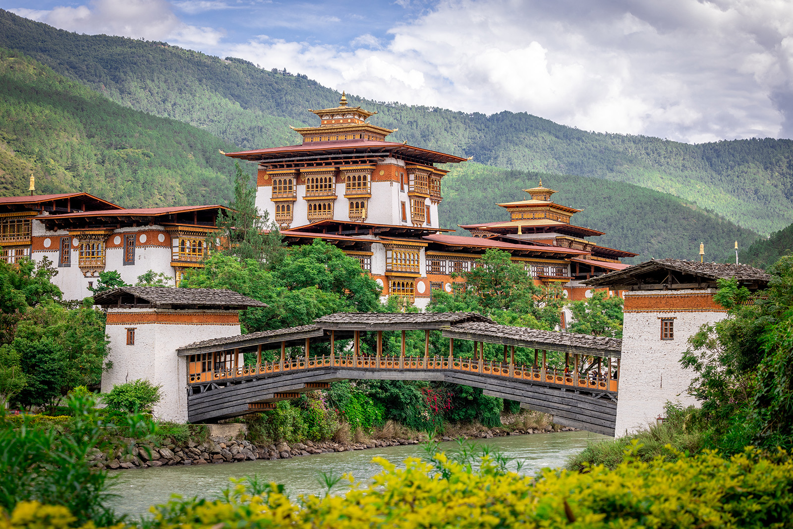Large white and bronze temple with a wooden bridge below