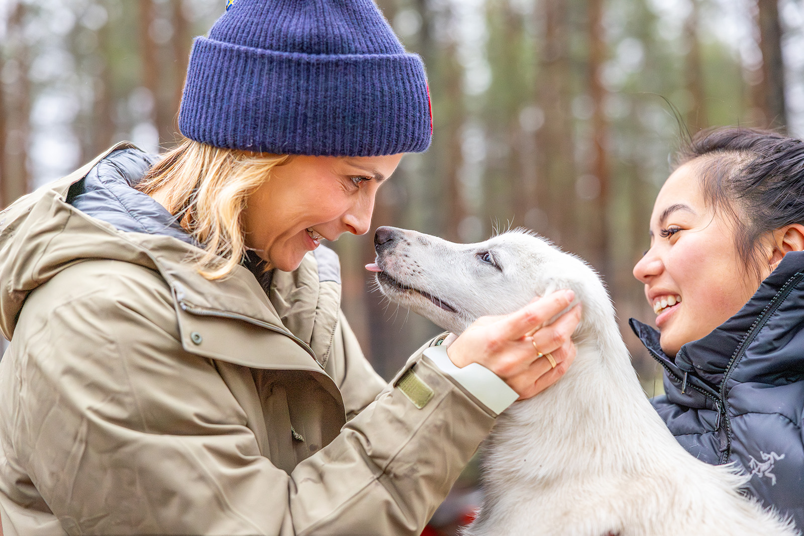 Two women smiling while holding onto a dog