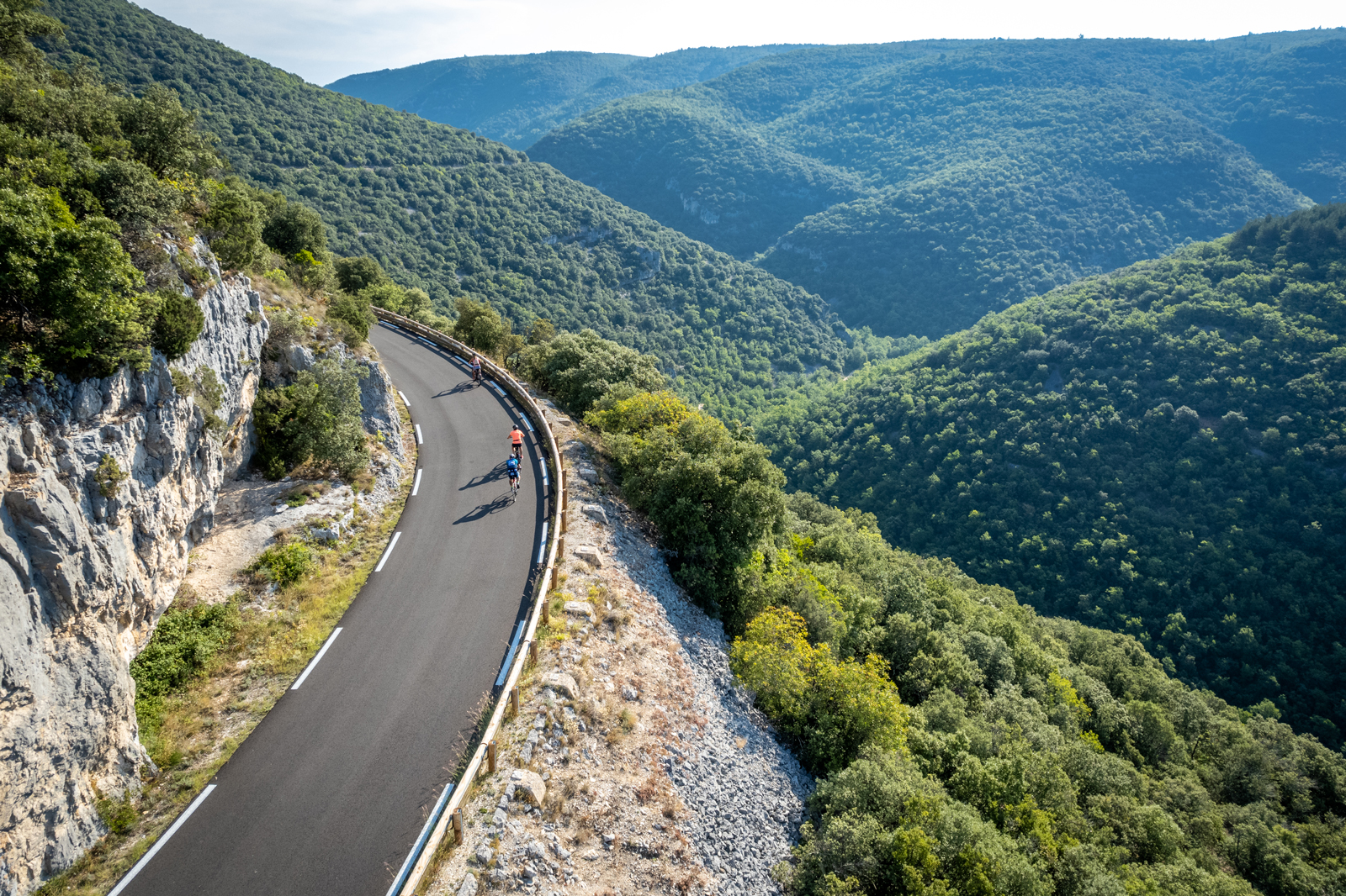 Group of people riding bikes on a road on a hill, grassy hills in the distance