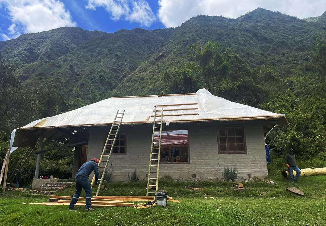 People with ladders building a roof on a small home