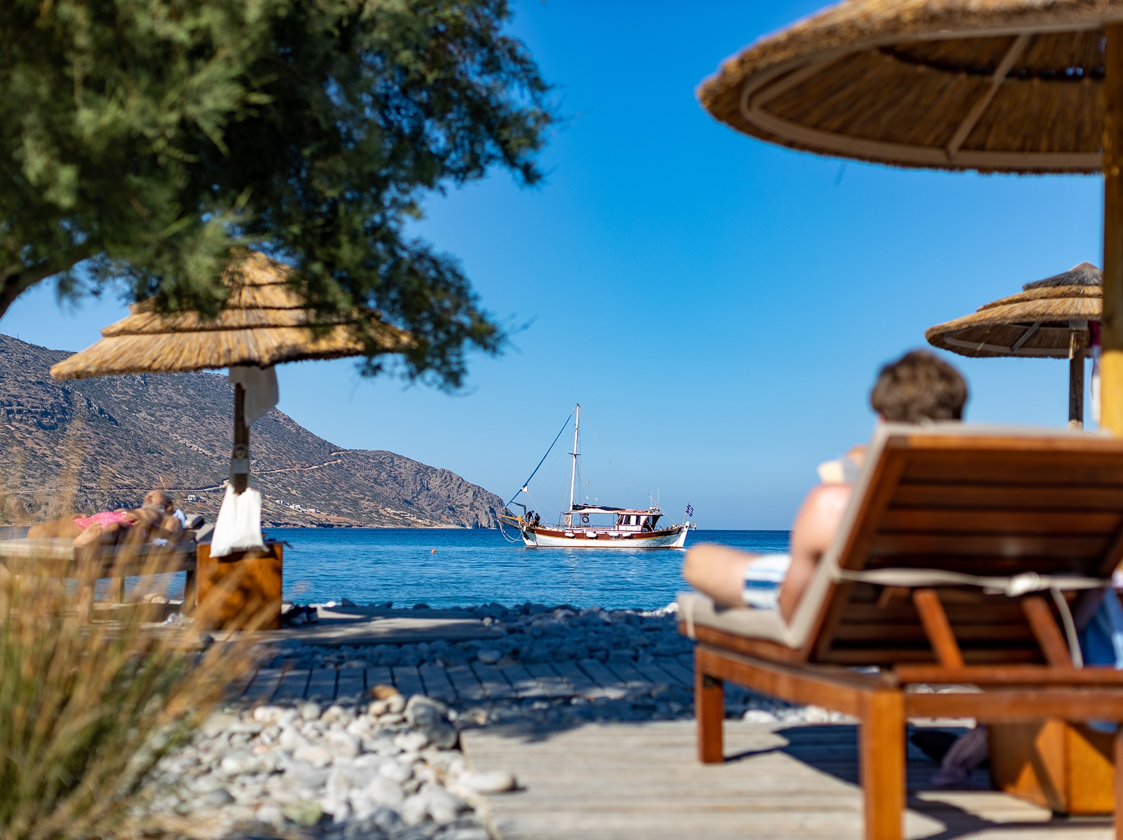 People sitting on reclining chairs by the shore of an ocean