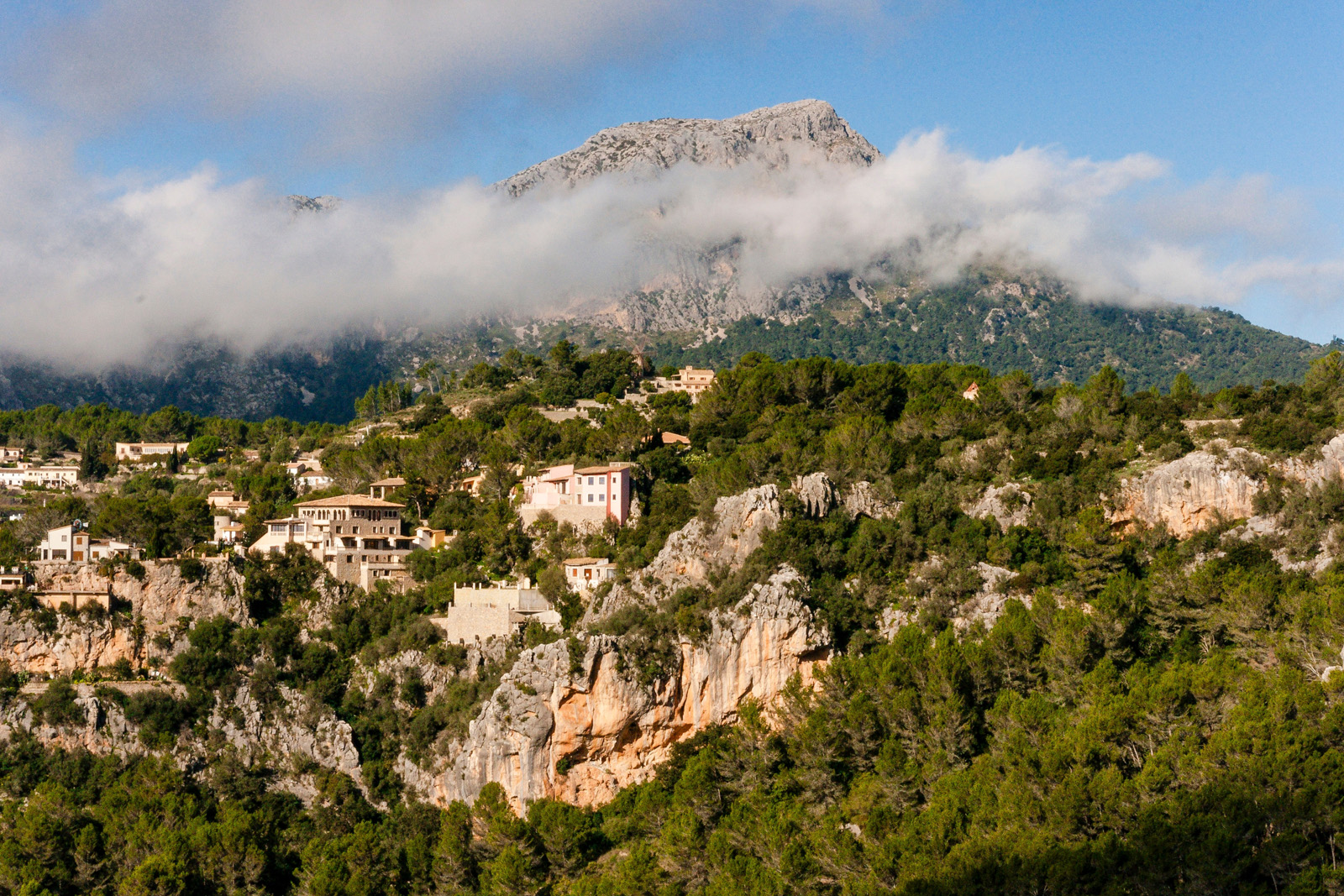 Large cliff with houses on top and foggy mountains in the distance