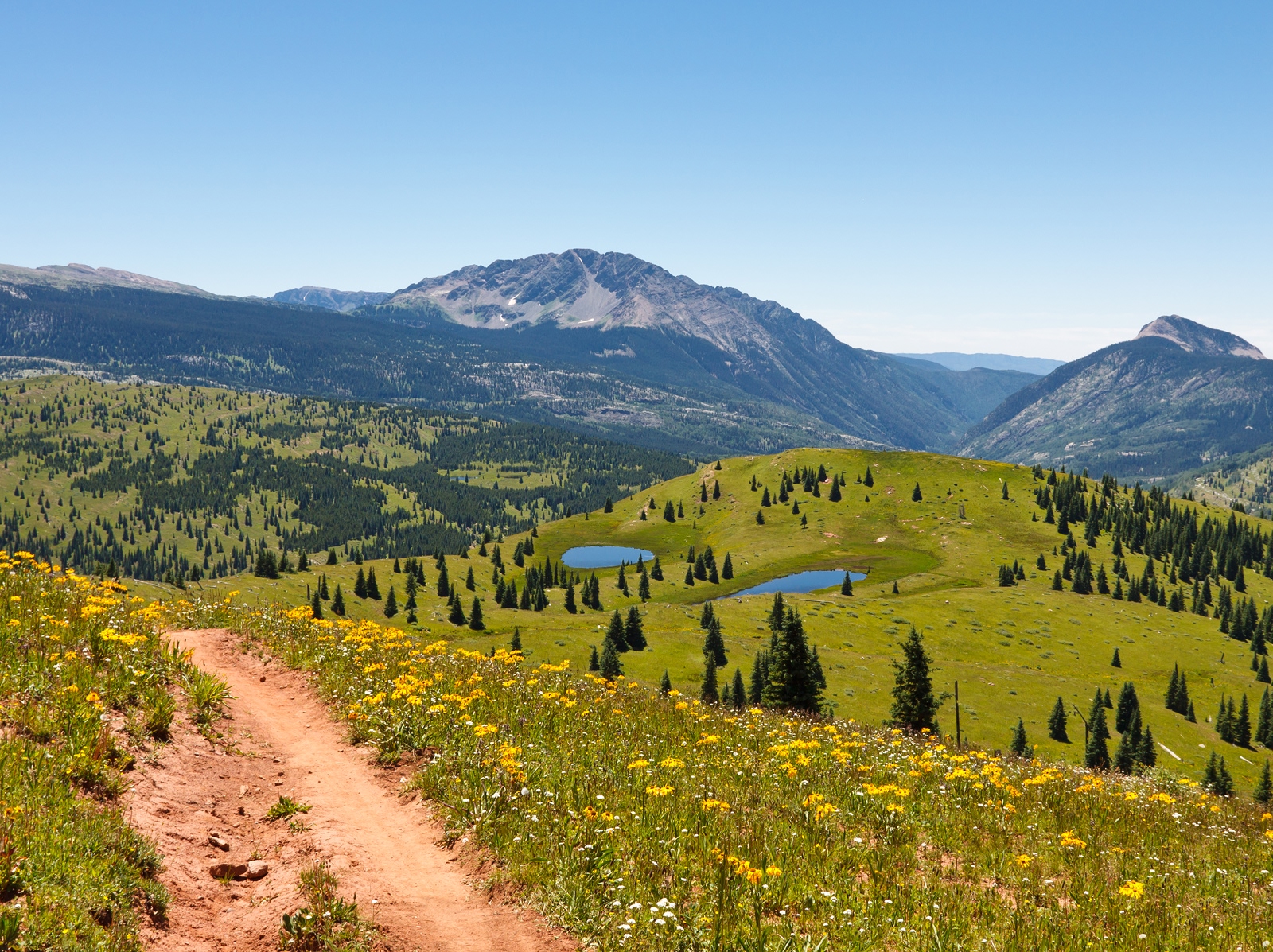Dirt trail on top of a hill, with a large valley in the distance