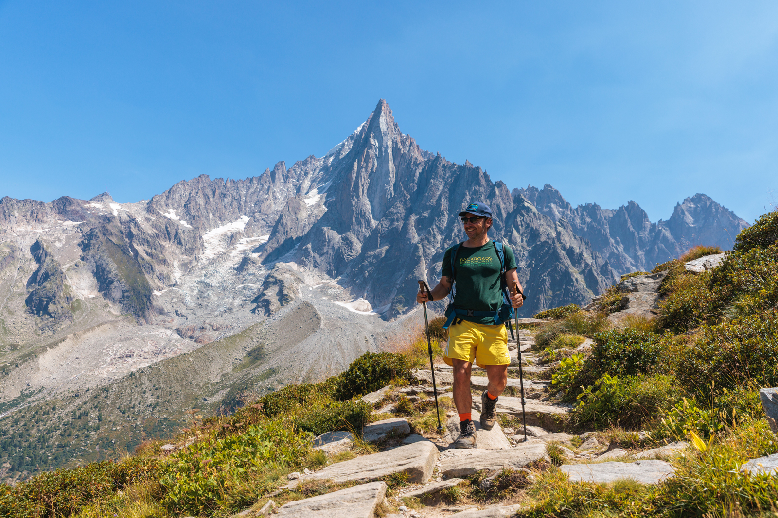 Hiker with hiking poles in front of steep mountain