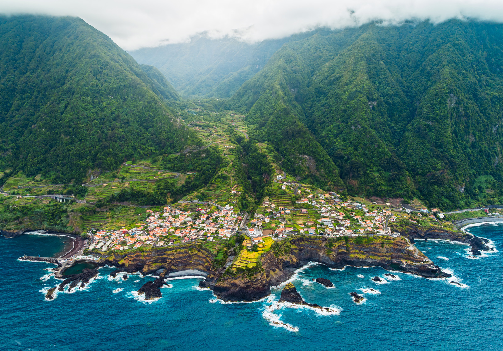 Sky view of a coastal town by large cliffs, next to the ocean
