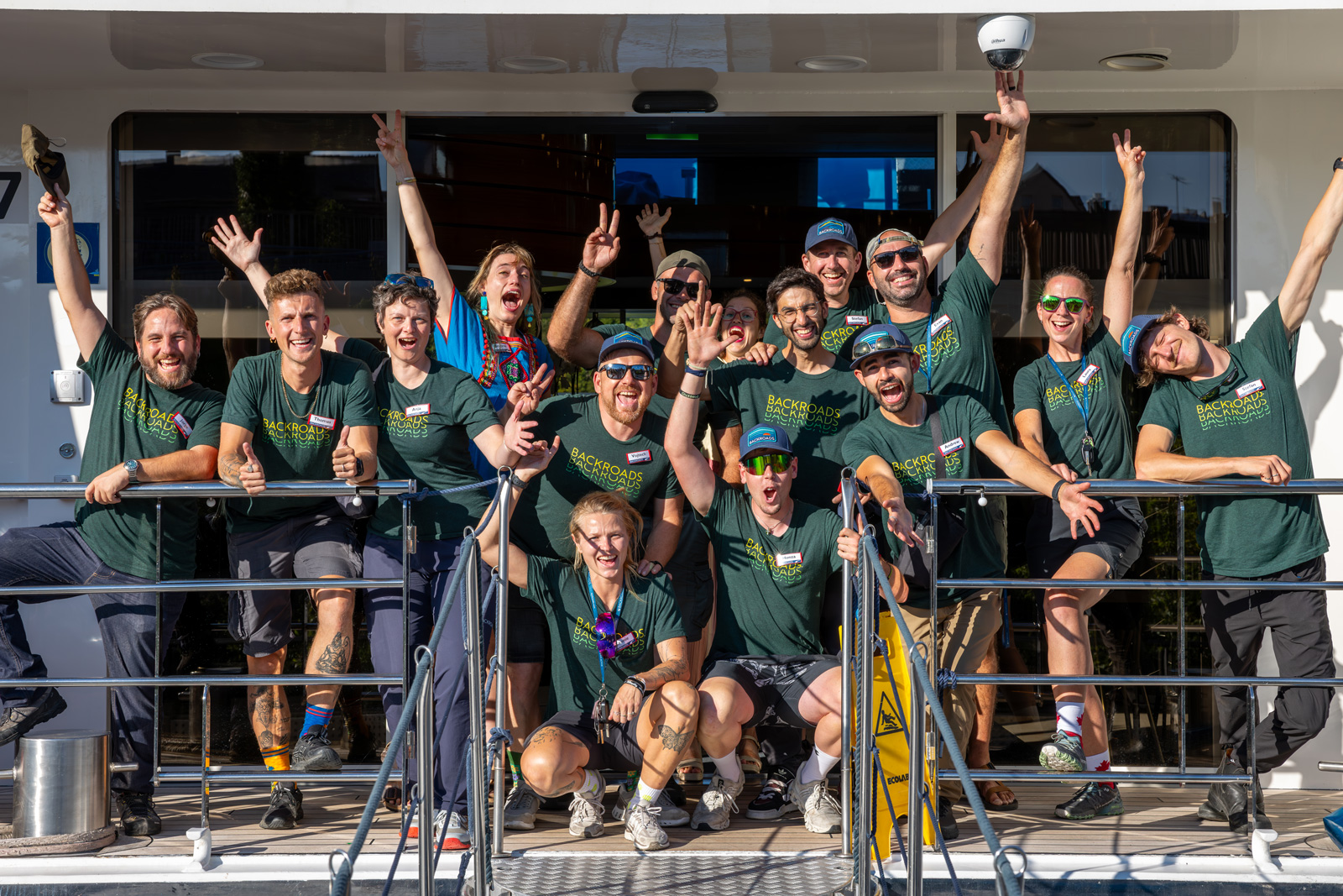 Group of people wearing green t-shirts, smiling with their arms in the air