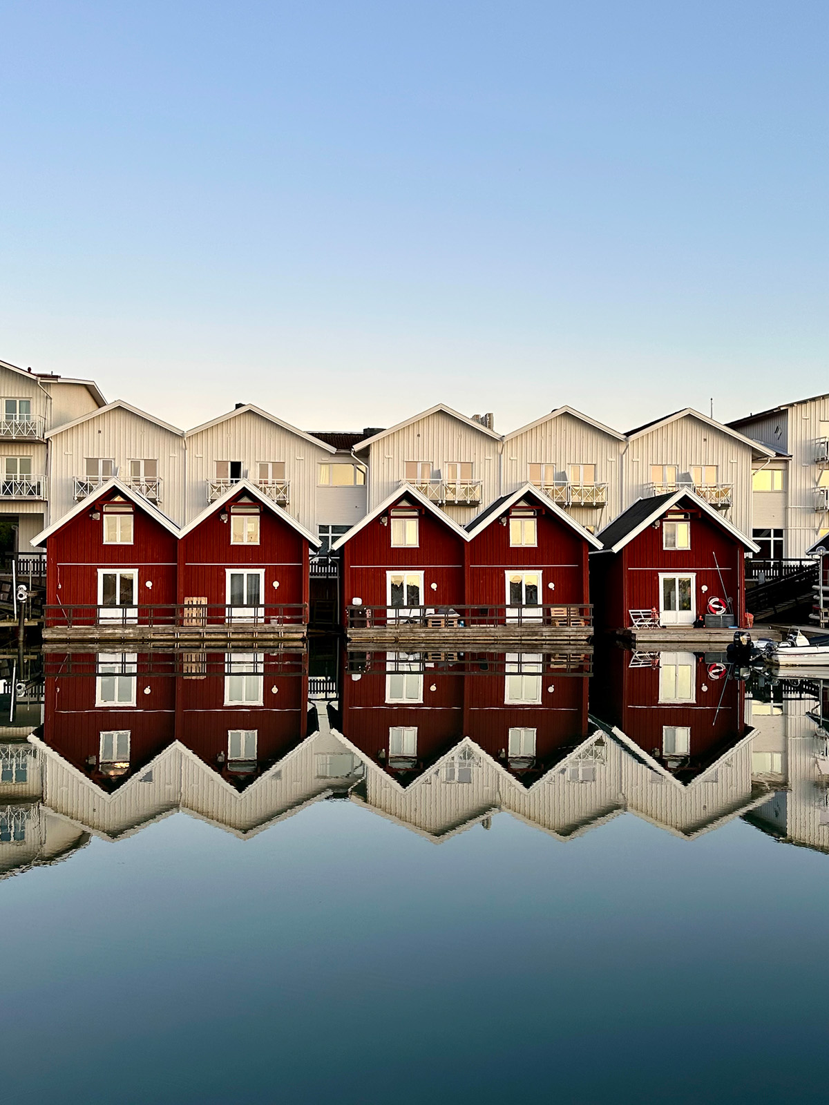 Five red houses with mountains in the back and a lake showing reflection