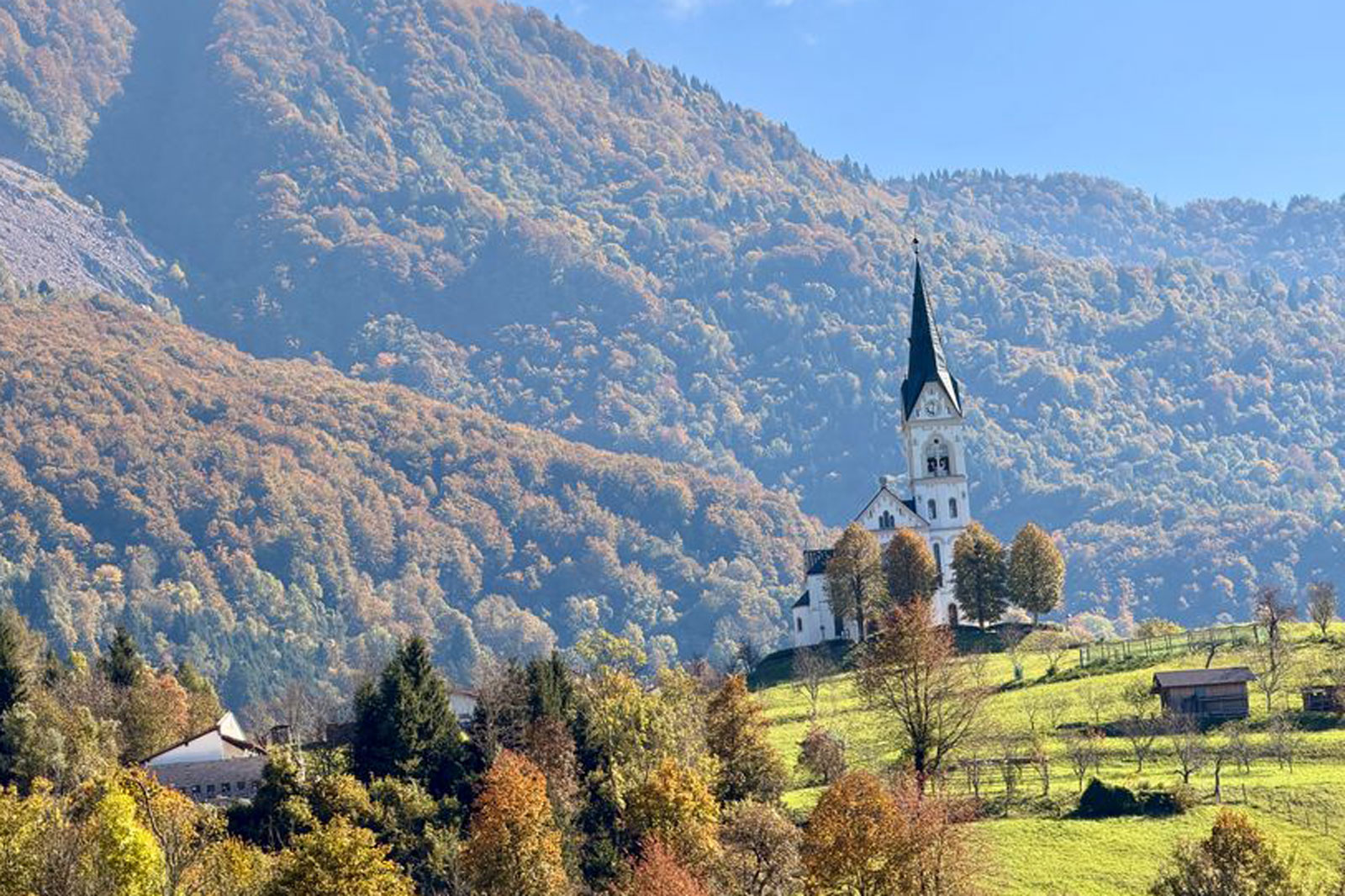 Church building in the middle of a grass field with a large mountain in the background