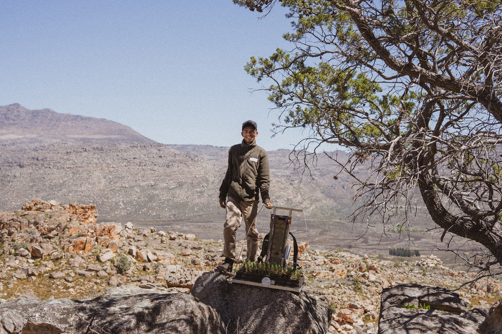Man standing on top of a log in the middle of a desert