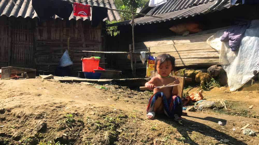 Vietnamese child carving wood with a Machette