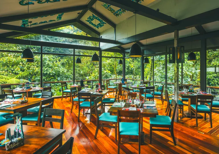 Indoor dining hall filled with wooden tables and blue chairs