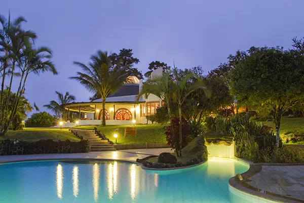 swimming pool lit up at night next to hotel