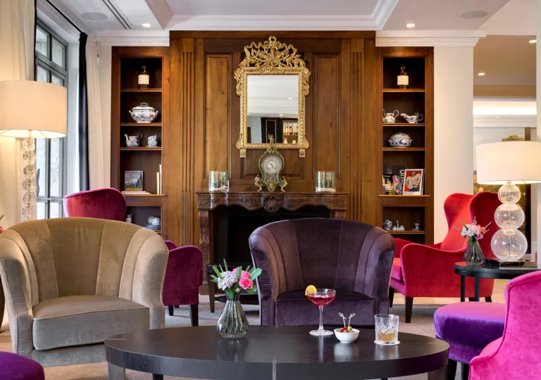 Indoor lounge with purple and gray cushioned chairs in front of a fireplace