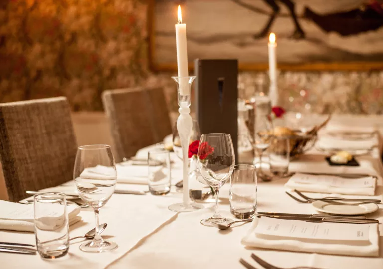 Indoor dining table with menus and candles on the table, surrounded by wine glasses