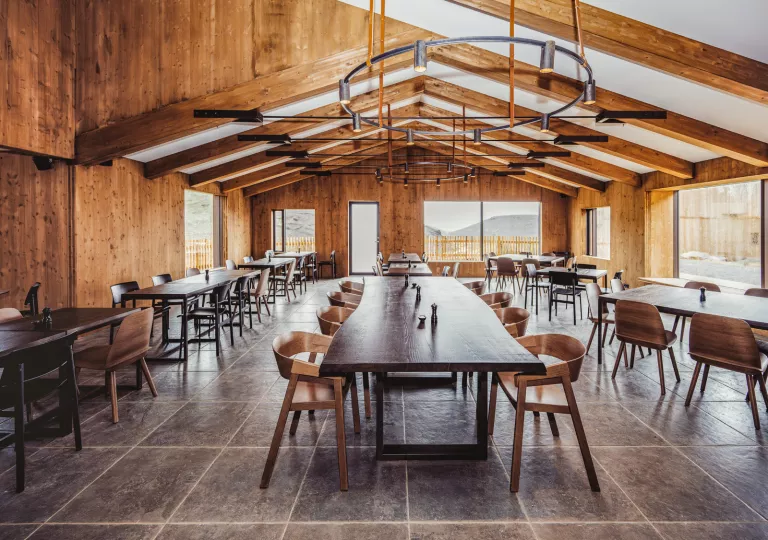 Indoor dining area with long wooden dining tables and wooden chairs around each table
