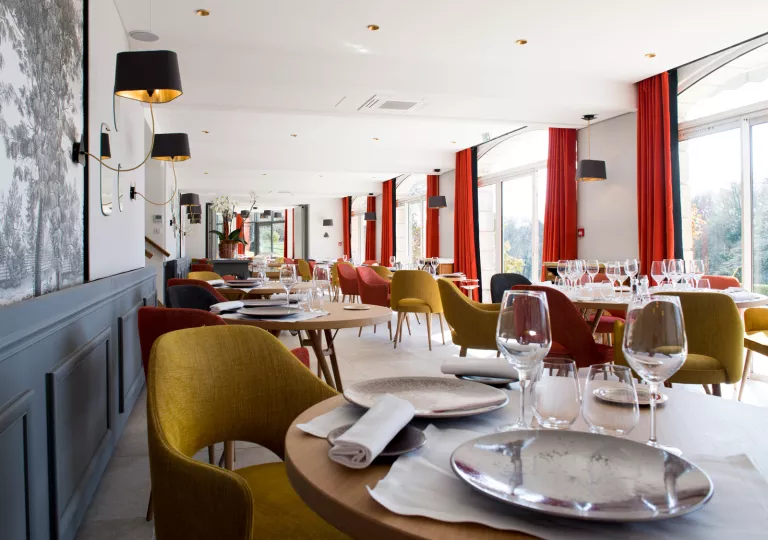 Long dining area with wine glasses and plates on each table