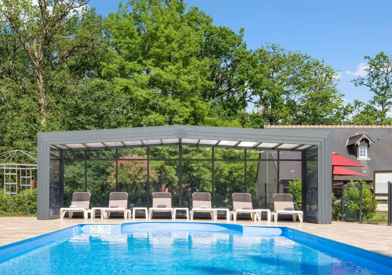 Outdoor pool with brown chairs under a glass canopy covering