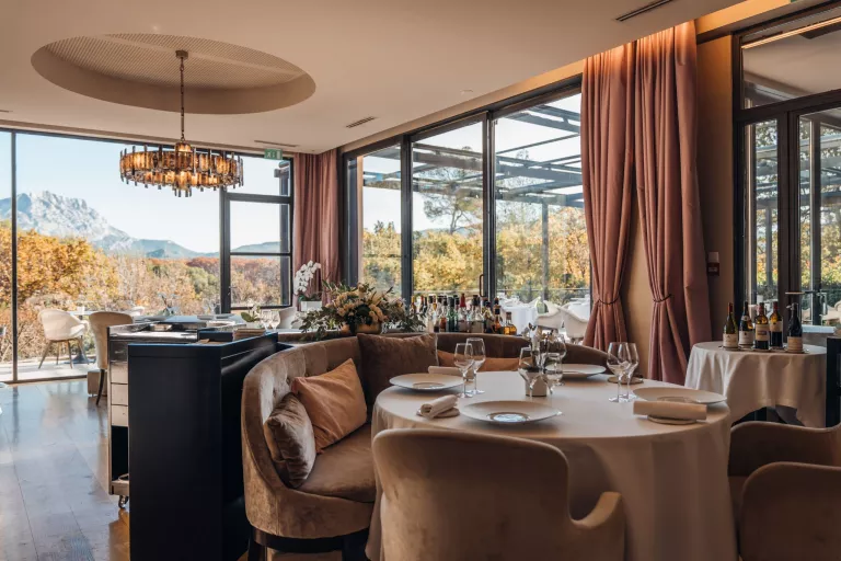 Indoor dining area with large, tan curtains and an open area looking out towards mountains