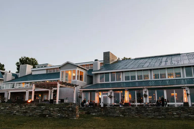 Exterior view of green and white building with an outdoor, stone patio