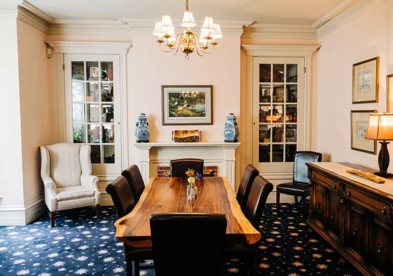 Indoor seating area with a wooden table and leather chairs, with painting on the walls