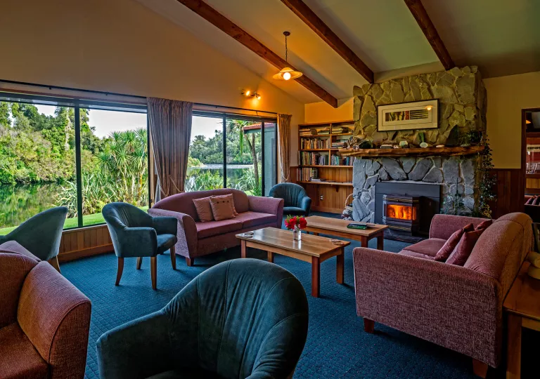 Seating area with red and green sofas and a stone fireplace in the center