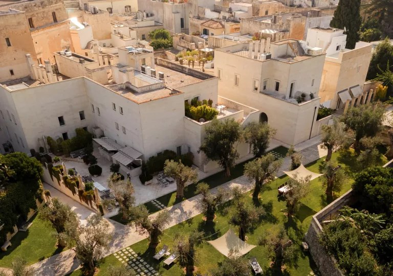 Top view of white buildings surrounded by trees and outdoor tables
