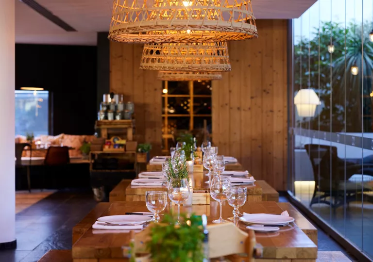 Wooden tables with wine glasses and woven ceiling light fixtures