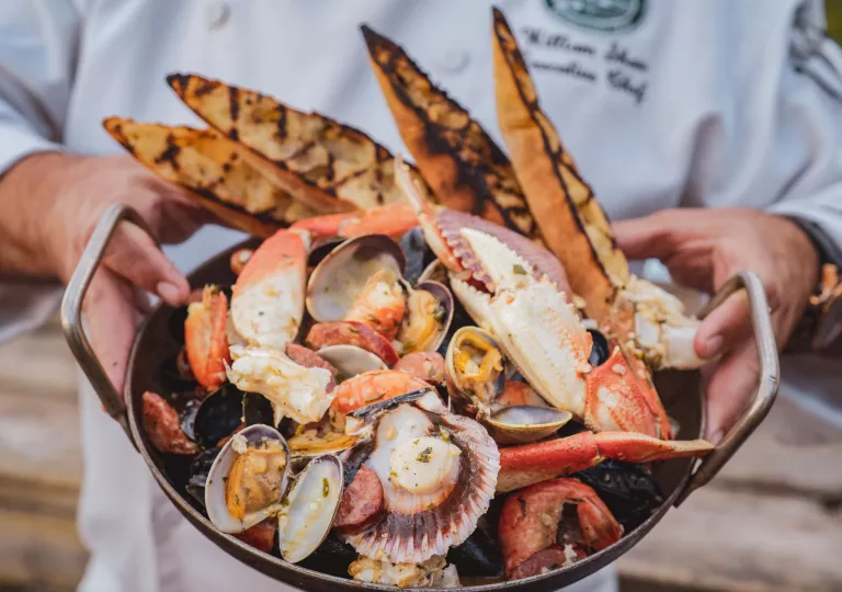Person holding up a plate full of seafood with 4 slices of charred bread