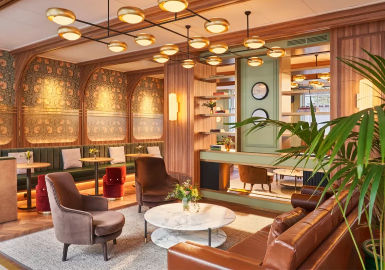 Lounge with wooden walls and cushioned sofas and chairs around circular tables