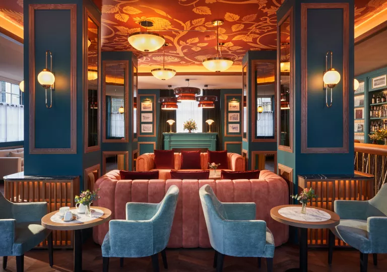 Blue lounge room with red and blue cushioned chairs and large light fixtures