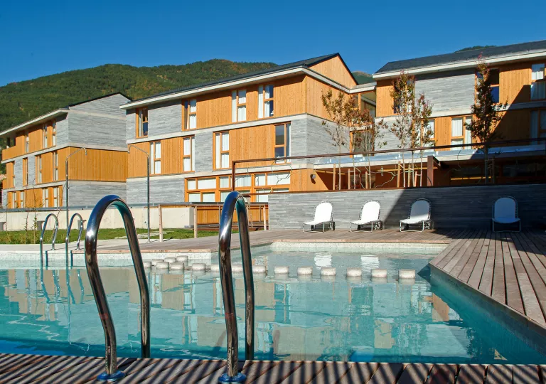 Outdoor pool next to a wood and stone hotel building