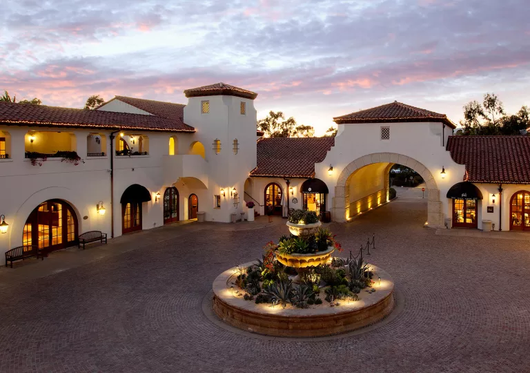 Courtyard with a circular fountain with white and tan buildings surrounding