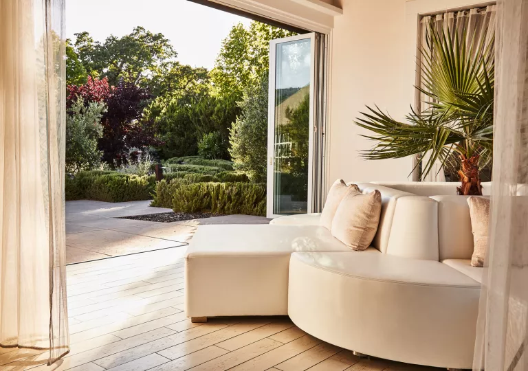 White cushioned couch with open doors leading to a garden