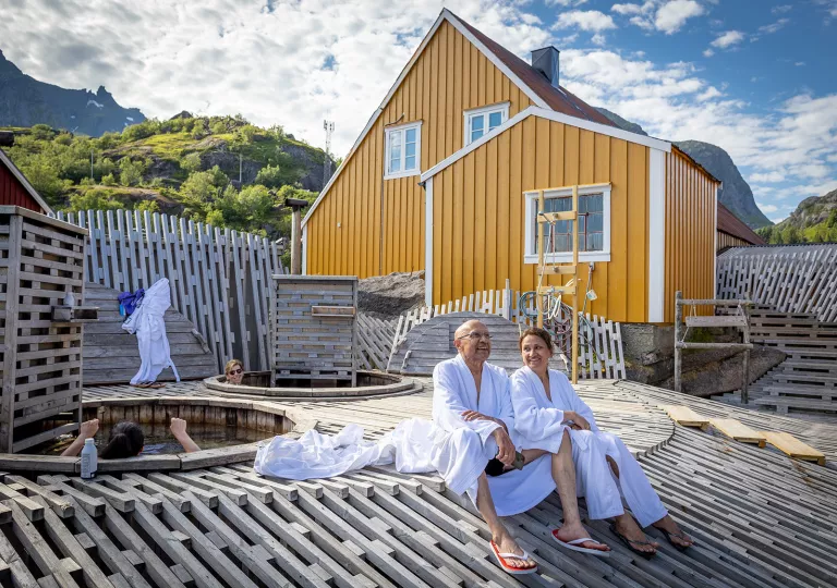 Man and woman in bath robes sitting outside next to hot tub baths