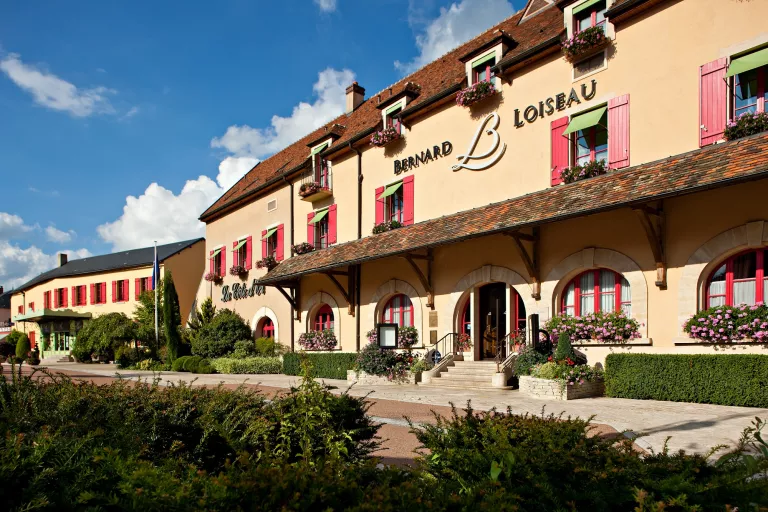 Exterior orange hotel building surrounded by trimmed bushes
