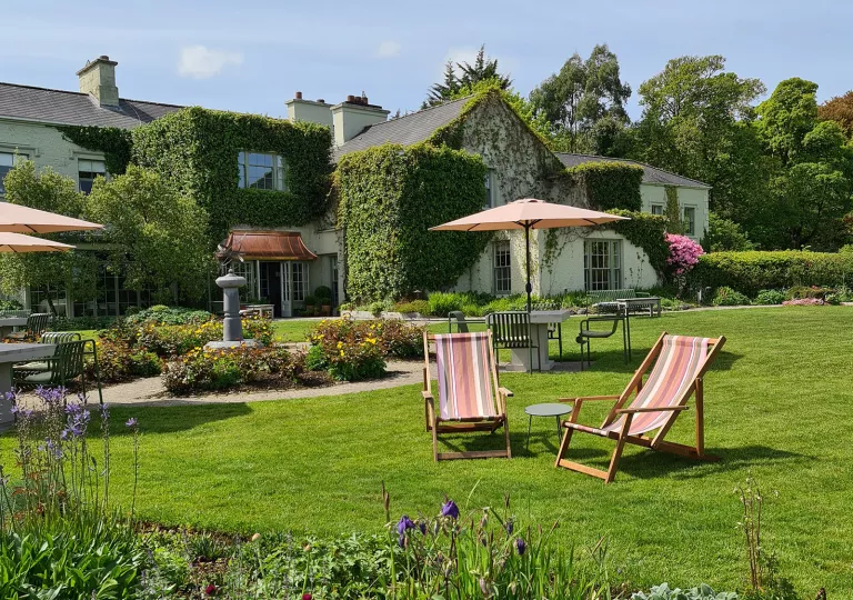 Outdoor patio and grass field with chairs, umbrellas and stone tables