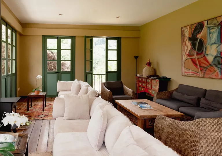 Room with cushioned white and gray couches, with green doors in the background