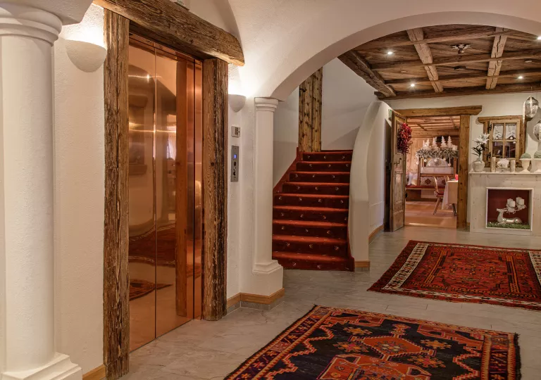 Hotel lobby with a bronze elevator and a small staircase to the right
