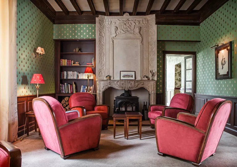 Seating area with large, red chairs and a stone fireplace in the center