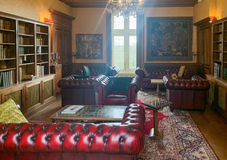 Library room with red leather couches and paintings on the walls